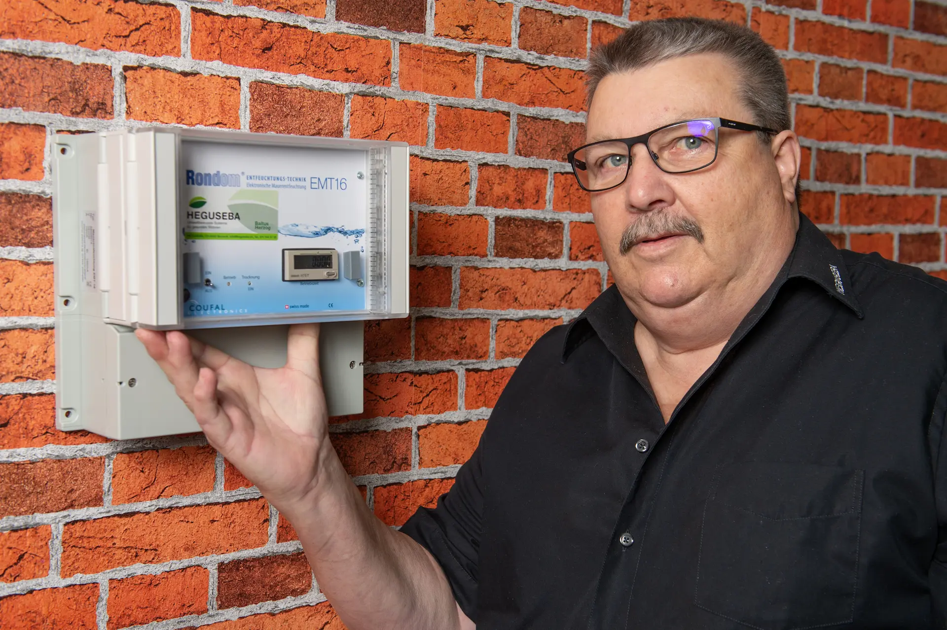 Heguseba Inhaber Baltus Herzog zeigt das EMT System, mit dem feuchte Kellerwände ohne bauliche Massnahmen getrocknet werden.